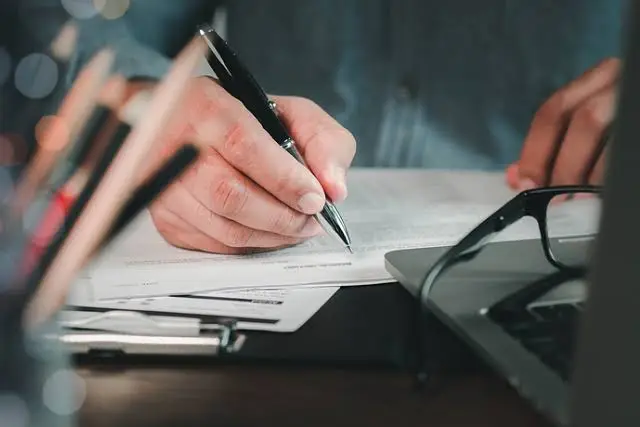 Image of a hand writing with black pen on a white paper