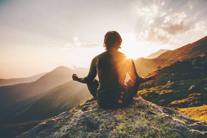Meditating between mountains during sunrise