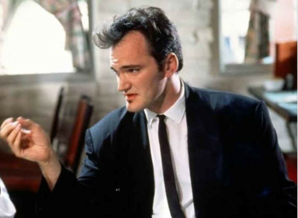 Man in black suit and tie having a conversation indoors