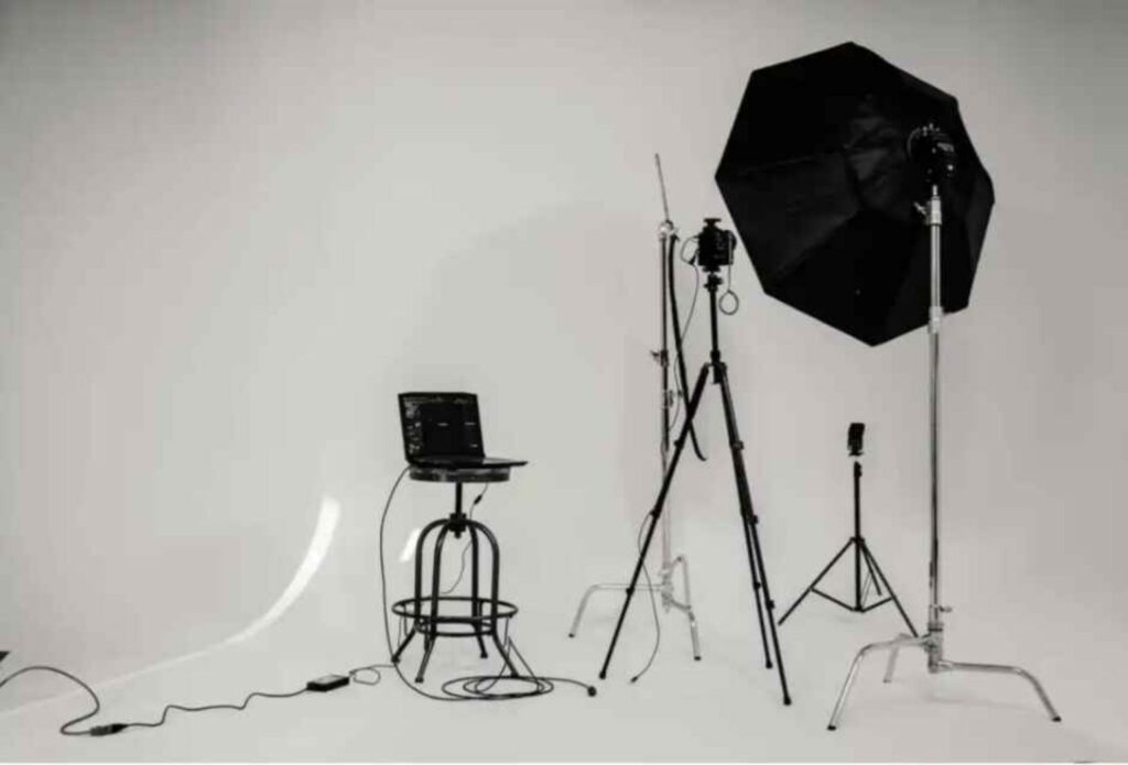 "Minimal product photography studio setup with camera, lighting, and laptop"