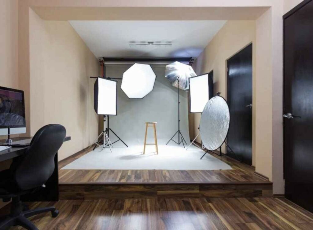 "Modern photography studio setup with lighting equipment, backdrop, and stool"