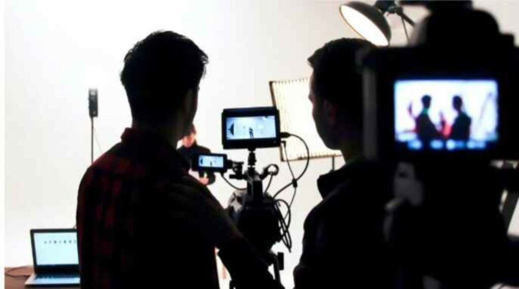 Camera crew filming on set during pre-production with lights, monitors, and professional filmmaking equipment.