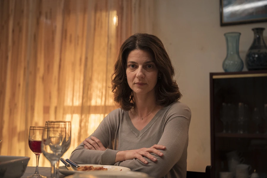 Barbara Ronchi as Licia sitting at a dinner table with a somber expression in Francesco Costabile's drama Familia.