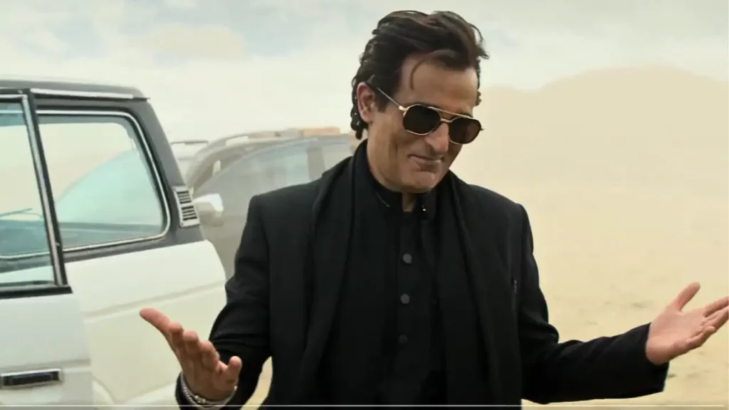 Akshaye Khanna in a stylish black suit performing a high-stakes desert action sequence in Dhurandhar, contributing to the film's record-breaking theatrical run.