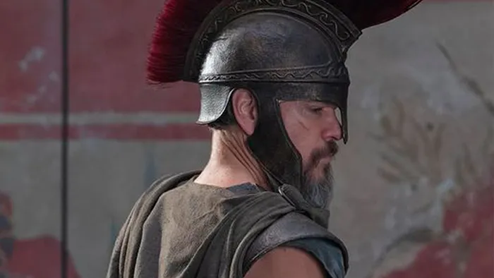 Ancient Greek warrior in bronze helmet with red plume, cinematic close-up from The Odyssey film adaptation