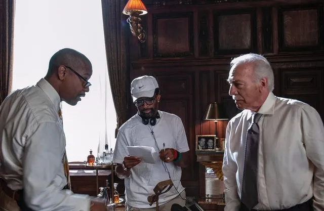 Director Spike Lee holding a script and giving direction to actors Denzel Washington and Christopher Plummer on the set of the heist movie Inside Man.