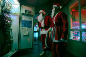 Two characters wearing Santa Claus disguises and fake beards standing in a server room during a scene from the Jingle Bell Heist movie.