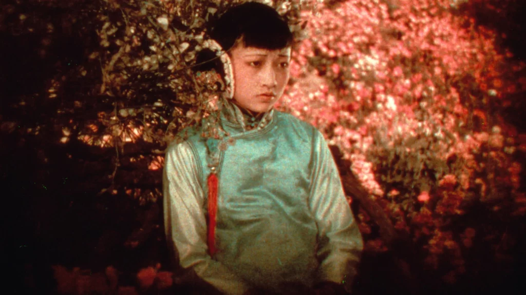 A film still of Anna May Wong from the 1922 movie The Toll of the Sea, showcasing the limited red and green color palette of the two-strip Technicolor process.