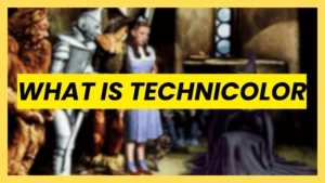A classic scene from The Wizard of Oz featuring Dorothy, the Tin Man, and the Scarecrow, with a bright yellow text banner reading "WHAT IS TECHNICOLOR".