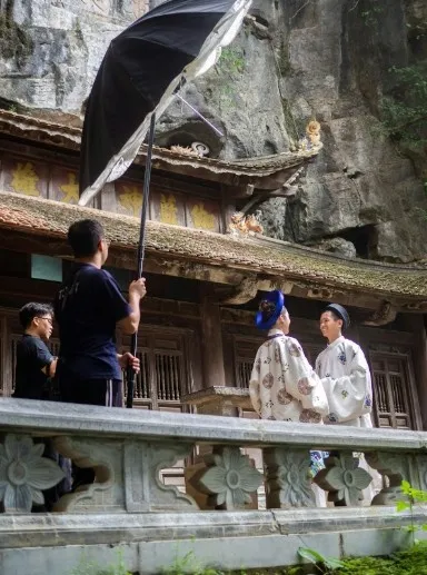 Film crew huddling under umbrellas during unexpected rain at a shoot location