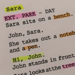 A close-up of a screenplay page marked with different colored highlighters indicating characters, props, and locations.