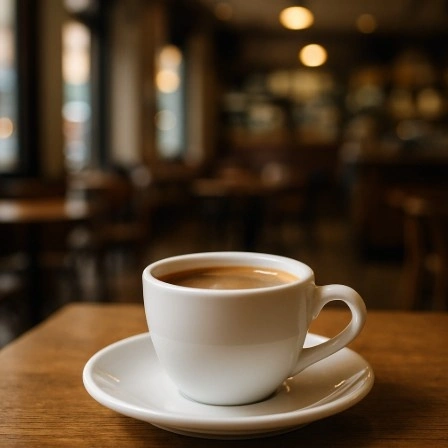 A close-up photo of a coffee cup on a table where the cup is perfectly sharp but the cafe background is beautifully blurred.