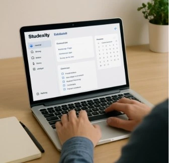 A person sitting at a clean desk using a laptop with the Studiovity dashboard visible on the screen.