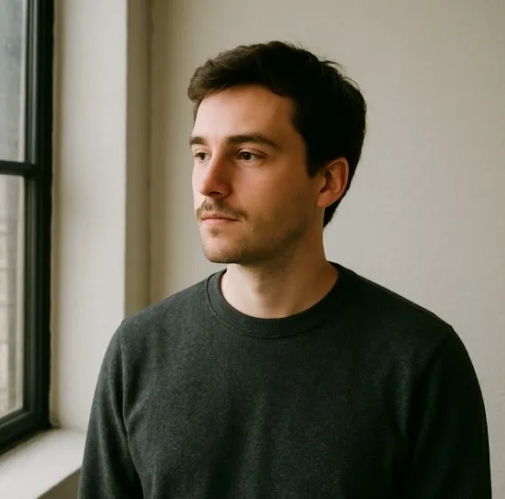 A person standing 45 degrees to a large window with a white wall opposite them acting as a natural fill.